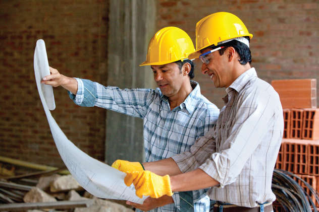 Two people in hardhats looking at blueprints